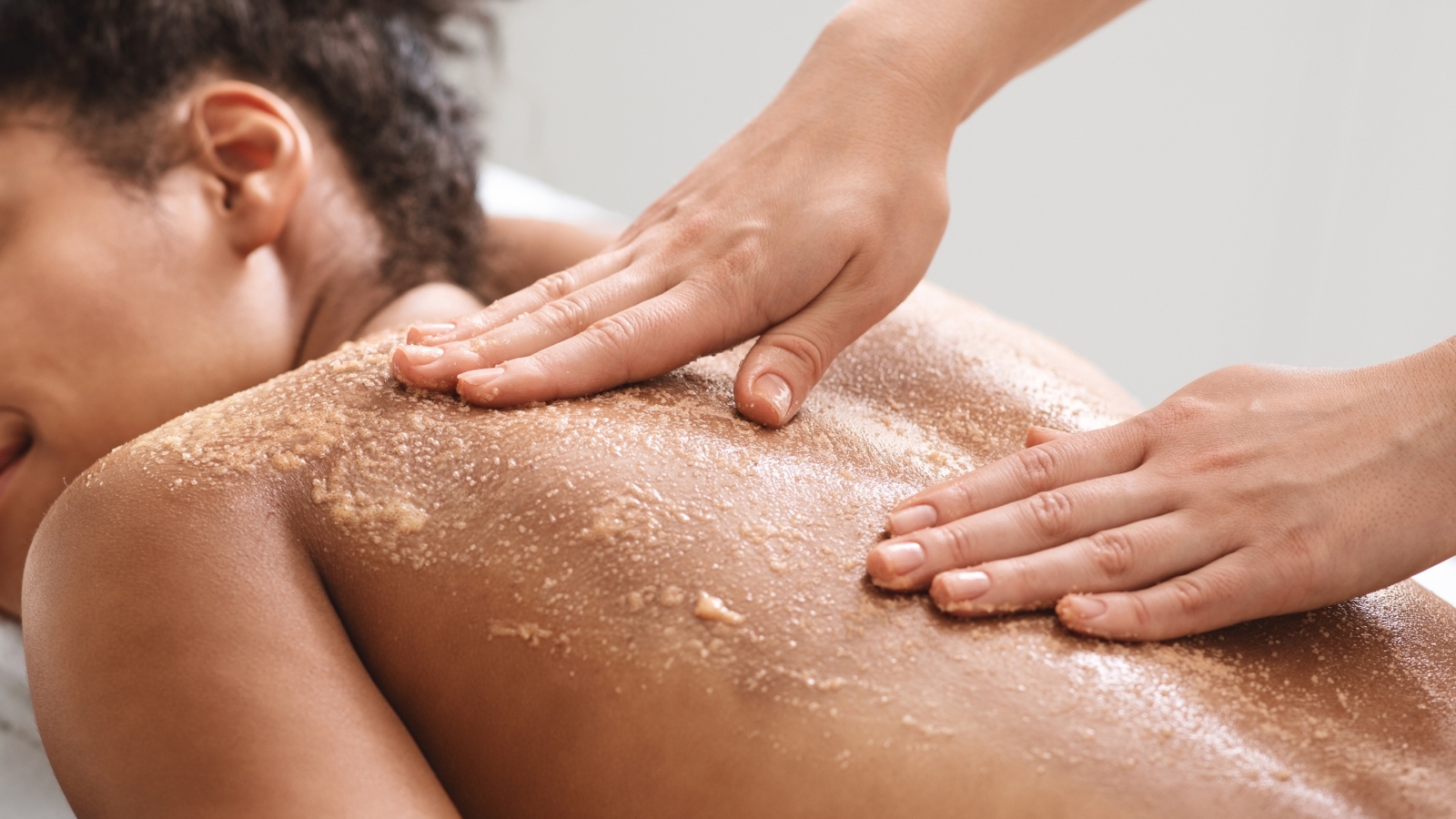 African american lady having skin scrubbing procedure at spa salon